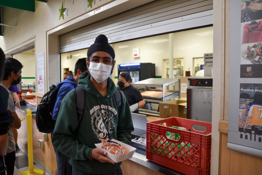Senior Ronak Momga picks up a free meal from the cafeteria during the lunch period. Students are expressing their overall content with the new statewide free lunch program, despite a few complaints regarding the actual food. The impact of the program on lower-income students is proving to be a significant aspect of the free lunches. “Even though it [the free lunch program] is not the best, I’m happy with it,” junior Audrey Guo said.