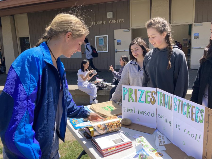 Senior Elizabeth Fetter flips through a vegan cookbook pointed out by club co-president Morgan Greenlaw. “All these materials are from PCRM, The Physicians Committee for Responsible Medicine,” Greenlaw said.