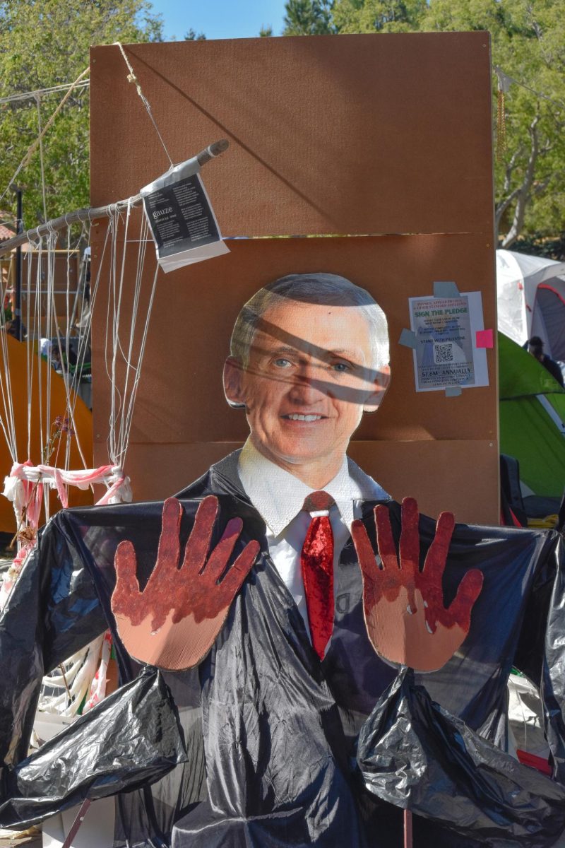 Cutout of Stanford President Richard Saller with “blood on his hands.” A visual statement made by the inhabitants of the encampments criticizes what they perceive as his role in the ongoing conflict in Gaza. It features a cutout of Richard Saller, Stanford’s president, along with a cardboard cut of hands stained with blood.