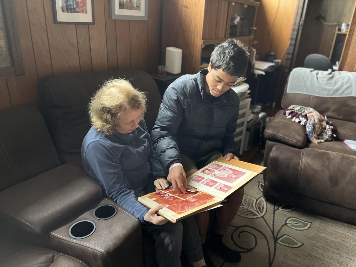 OLD MEMORIES — Kristine Taylor reminisces over old family photo albums with her grandson, Palo Alto High School senior Erik Taylor, remembering the days when she raised her kids in the more tightly-knit East Palo Alto.