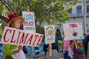  A member of the Raging Grannies holds a sign along with other protesters at the “Make Polluters Pay” protest at Palo Alto City Hall on April 18.
